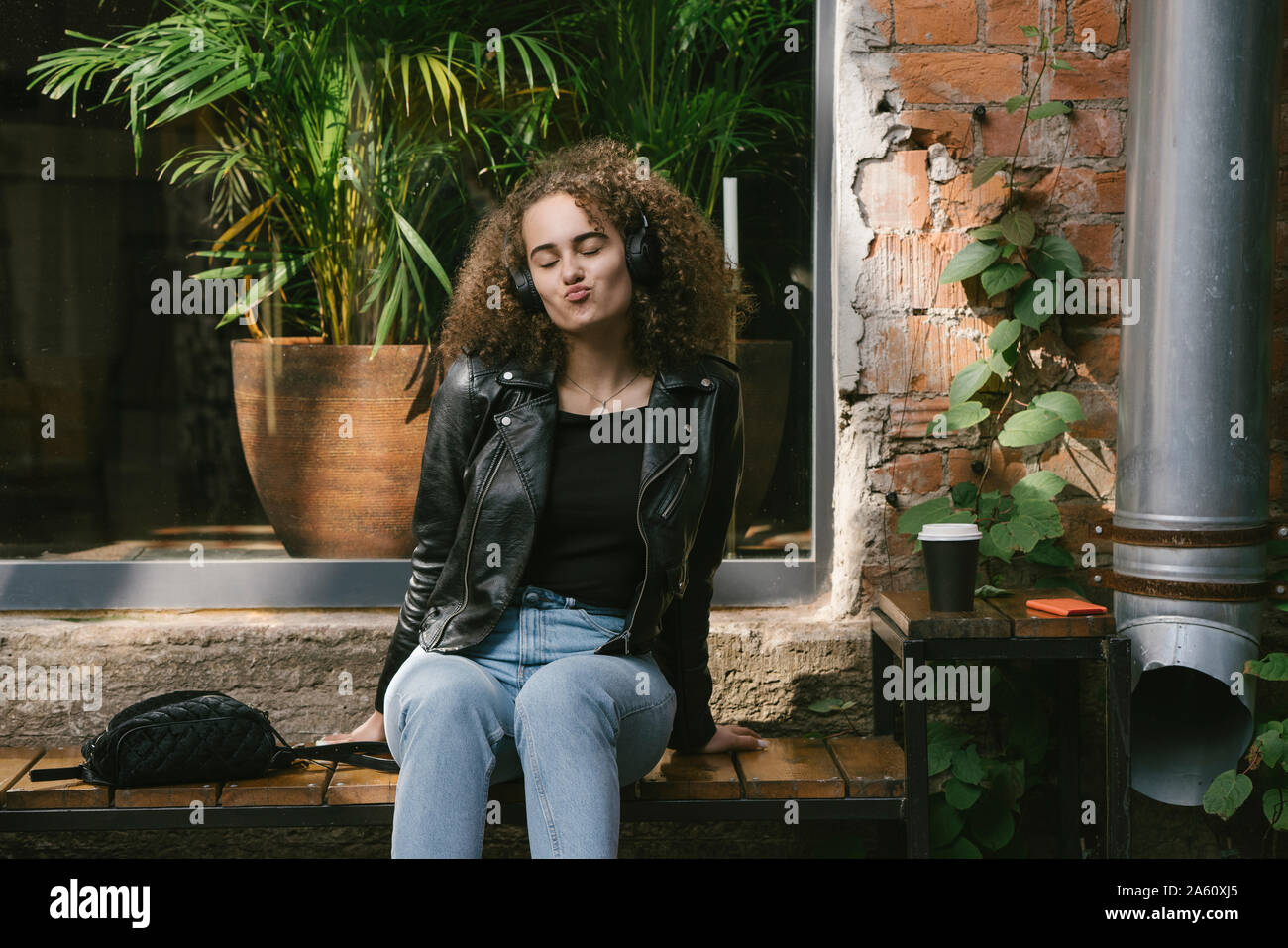 Portrait of teenage girl sitting at outdoor cafe musique d'écoute au casque et smartphone Banque D'Images
