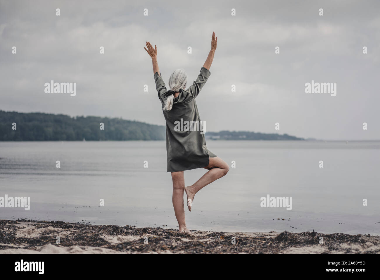 Senior woman looking at sea, debout sur une jambe, vue arrière Banque D'Images