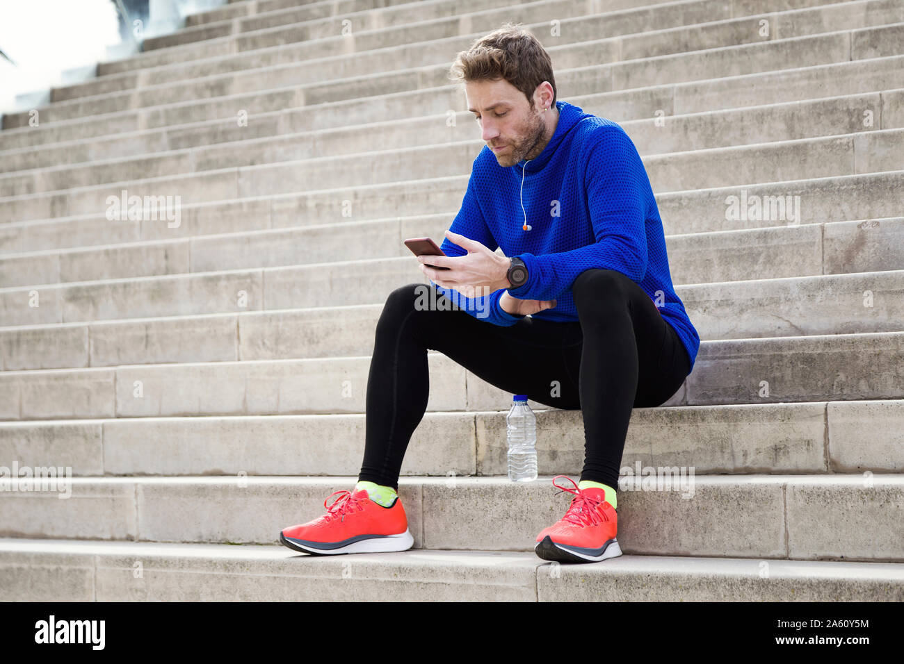 Jogger sitting on steps et using smartphone Banque D'Images