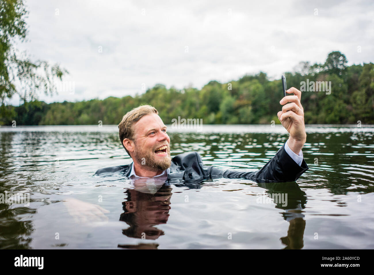 Mad businessman holding cell phone à l'intérieur d'un lac Banque D'Images
