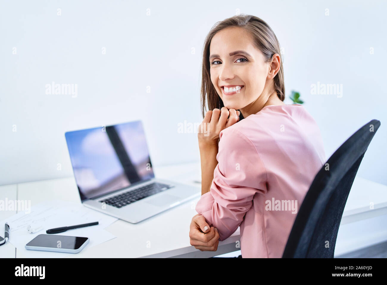 Cheerful young businesswoman smiling at camera while working in office Banque D'Images