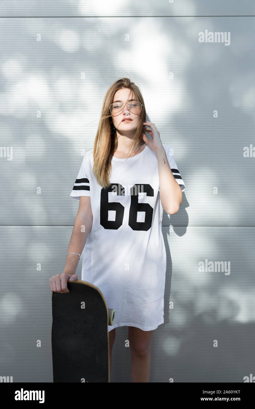 Jeune femme portant des T-shirt avec le numéro 66, holding skateboard Photo  Stock - Alamy