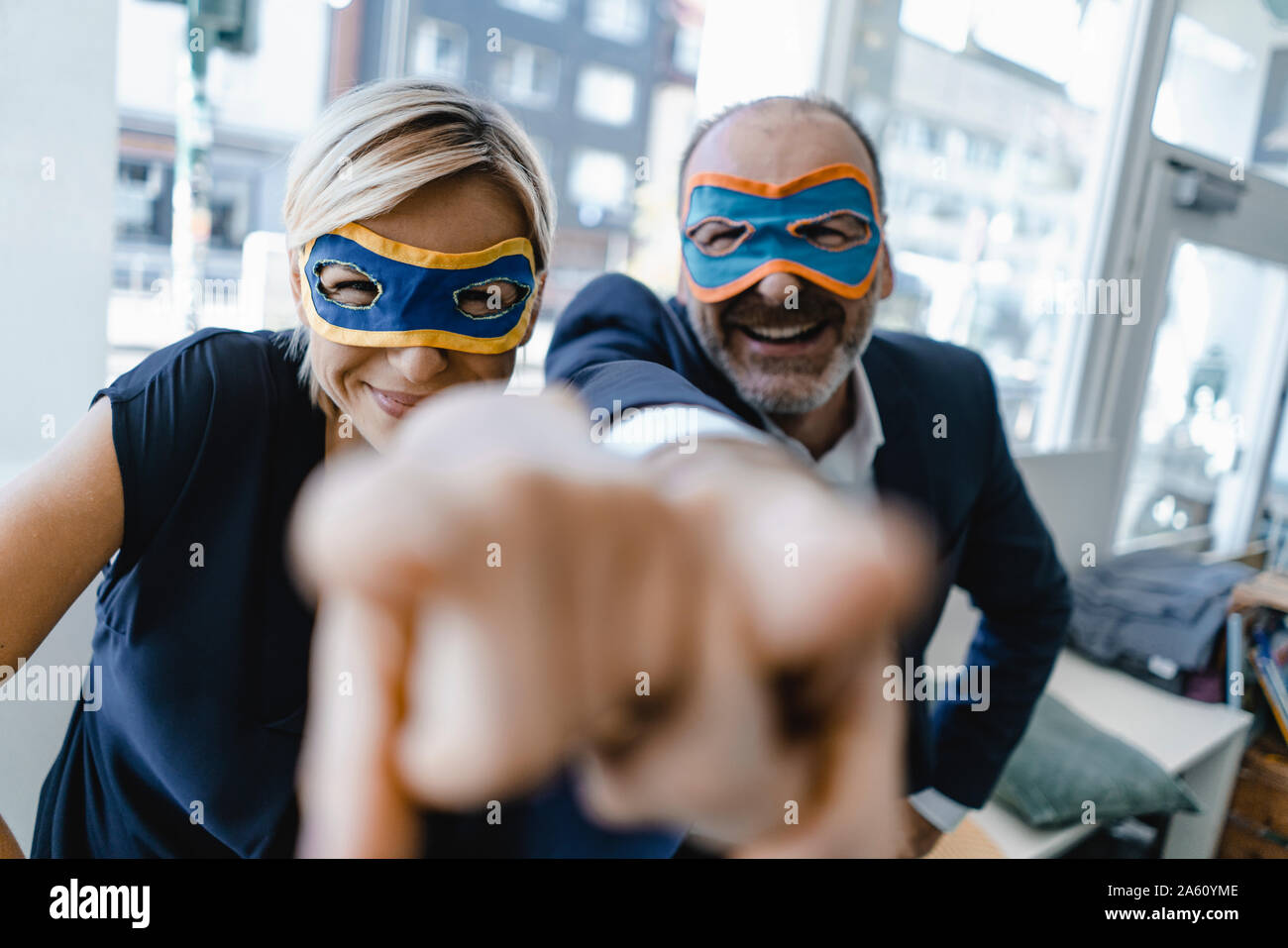 Homme d'affaires et femme, portant un masque de super héros, en pointant à huis clos Banque D'Images