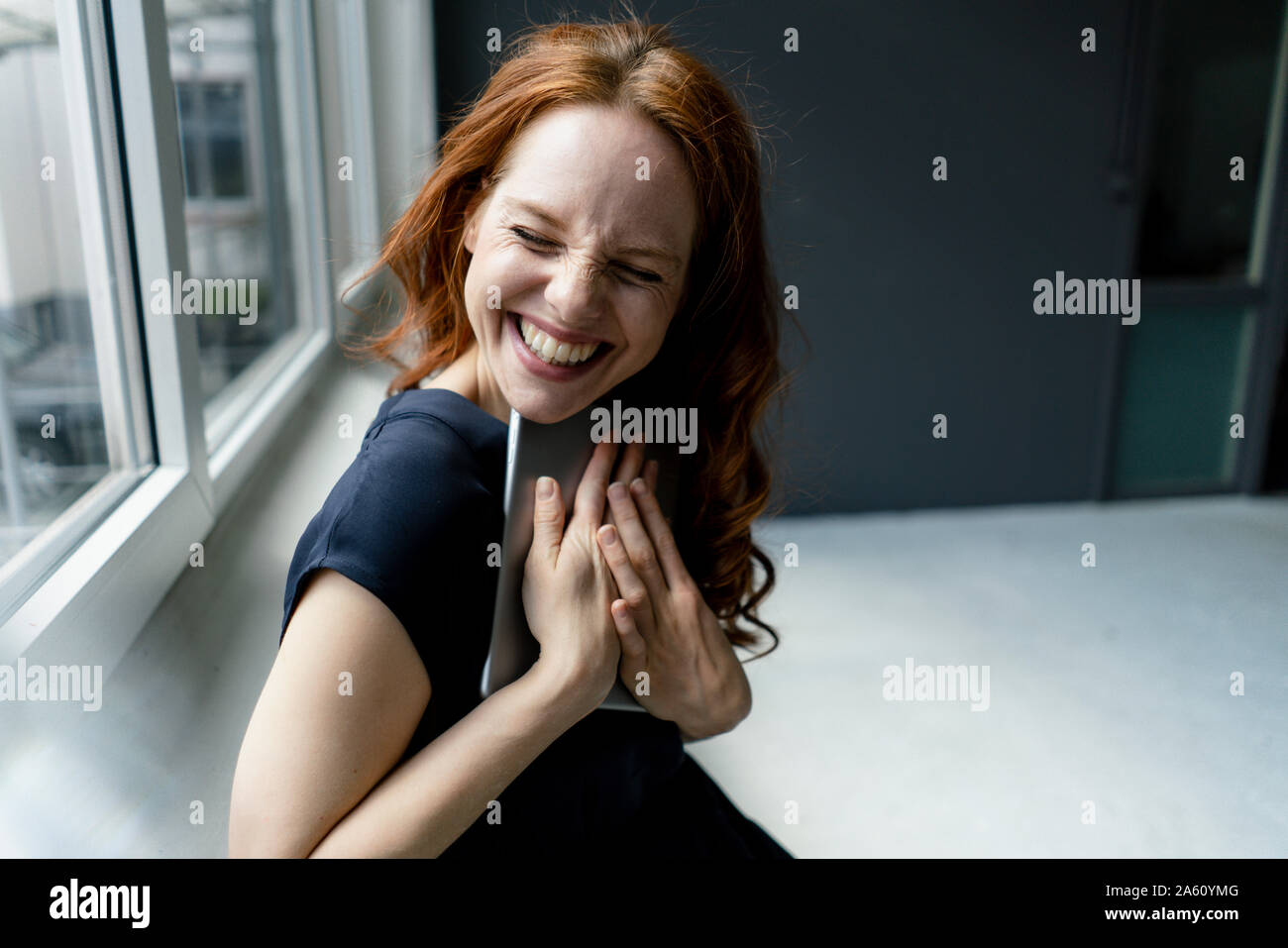 Portrait de femme rousse riant avec tablette numérique dans un loft Banque D'Images