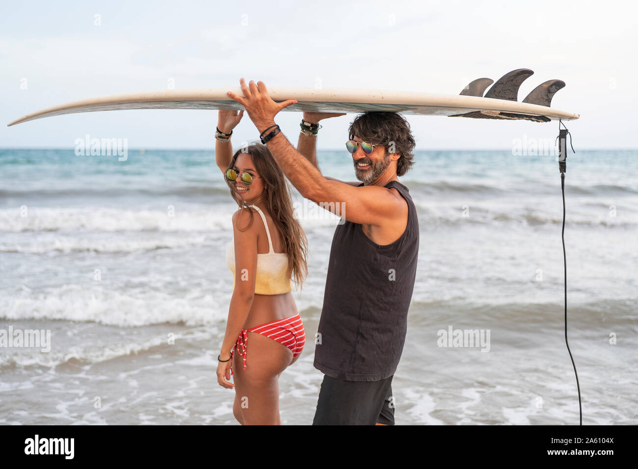 Jeune femme et mature man carrying surfboard ensemble à la mer Banque D'Images