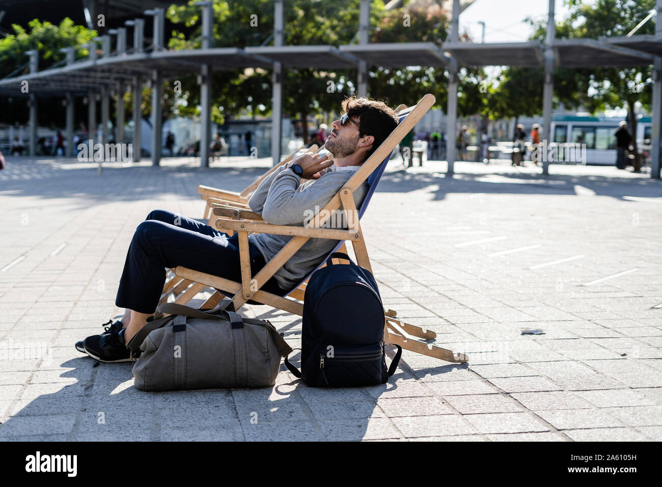 Man relaxing in deckchair sur place urbaine Banque D'Images