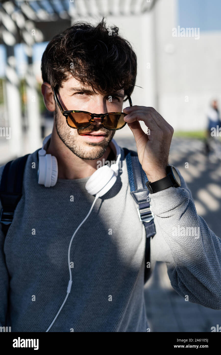 Portrait d'homme cool avec des lunettes et des écouteurs dans la ville Banque D'Images