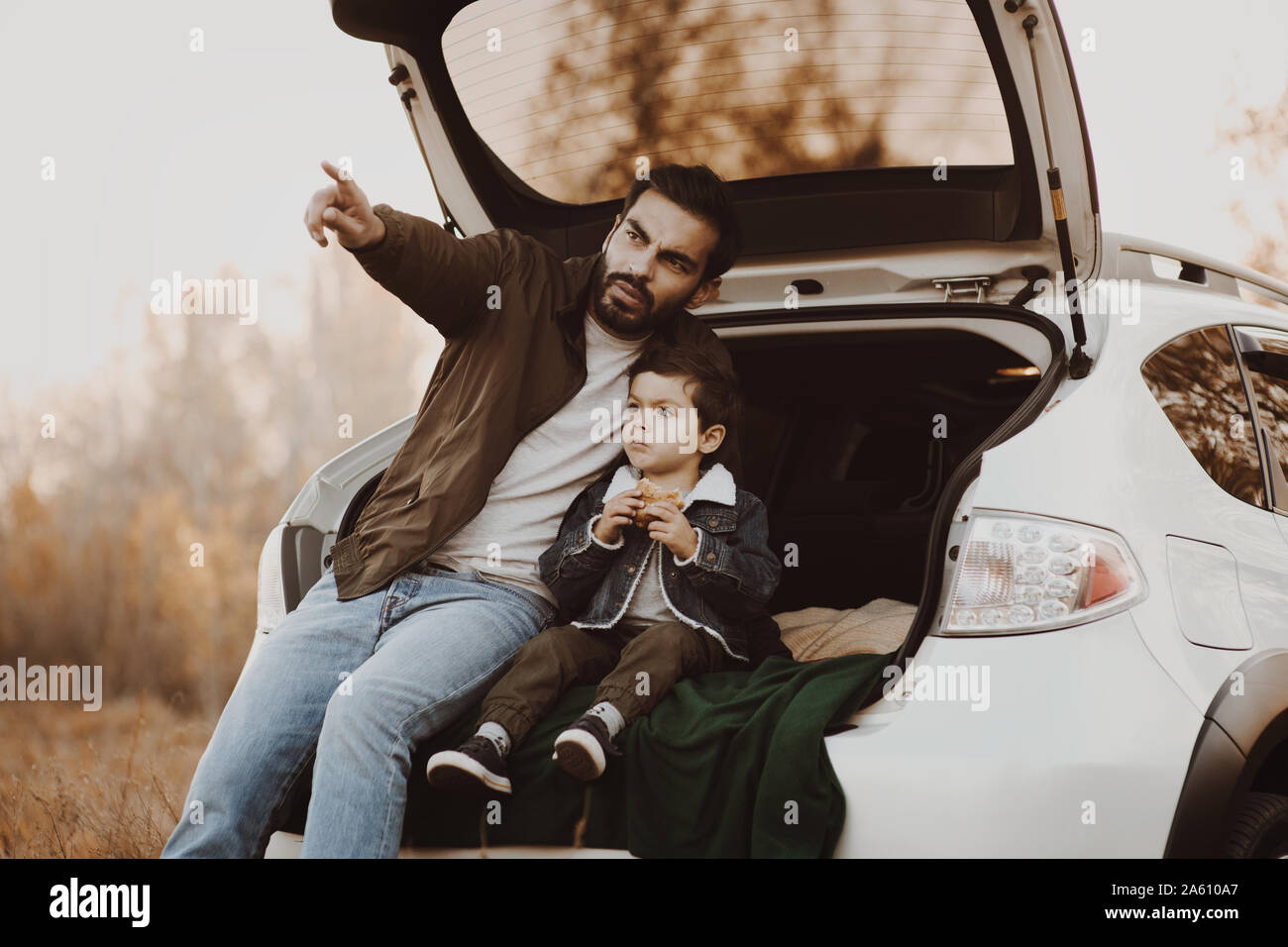 Père avec petit-fils having picnic dans coffre de voiture en automne pré. Banque D'Images