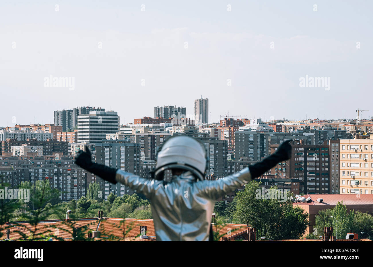 Vue arrière du garçon habillé avec les bras levés comme un astronaute dans la ville Banque D'Images