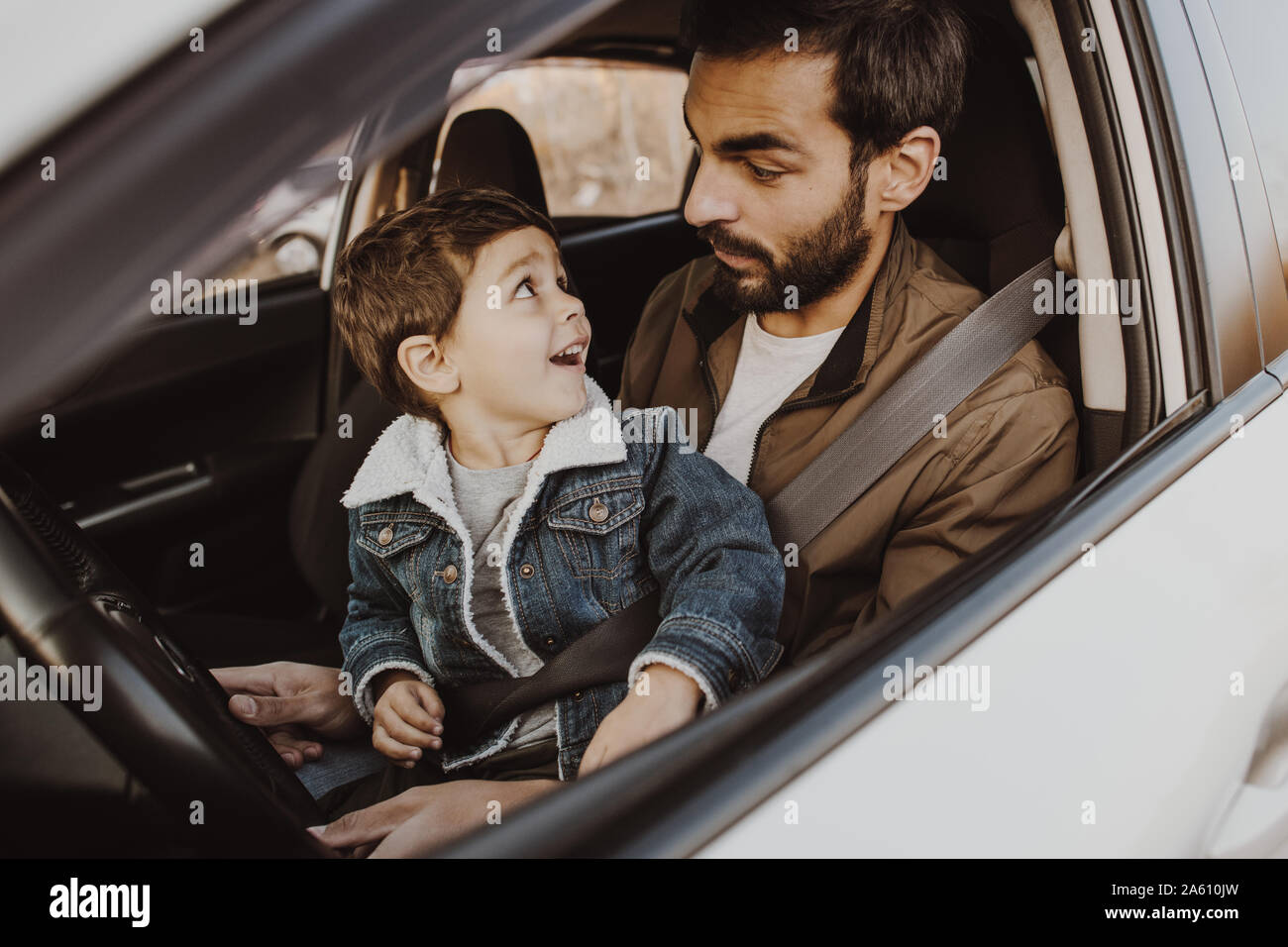 Heureux père jouant avec son fils dans le siège du conducteur dans sa voiture. Banque D'Images