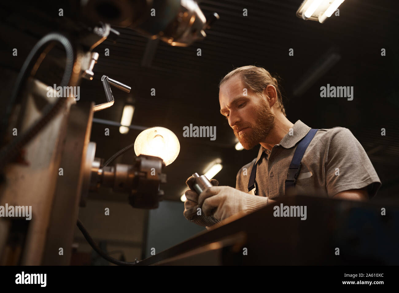 Travailleur manuel se concentrant sur son travail, il décisions détails métalliques sur le tour dans l'usine Banque D'Images