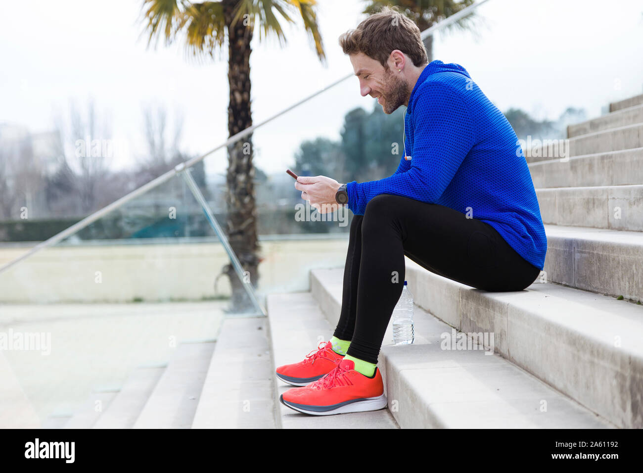 Jogger sitting on steps et using smartphone Banque D'Images