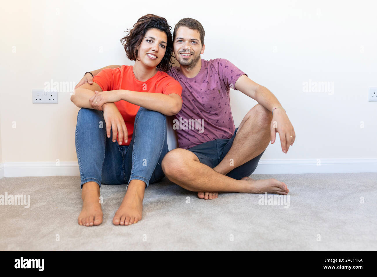 Portrait of happy couple assis sur le plancher à new home Banque D'Images