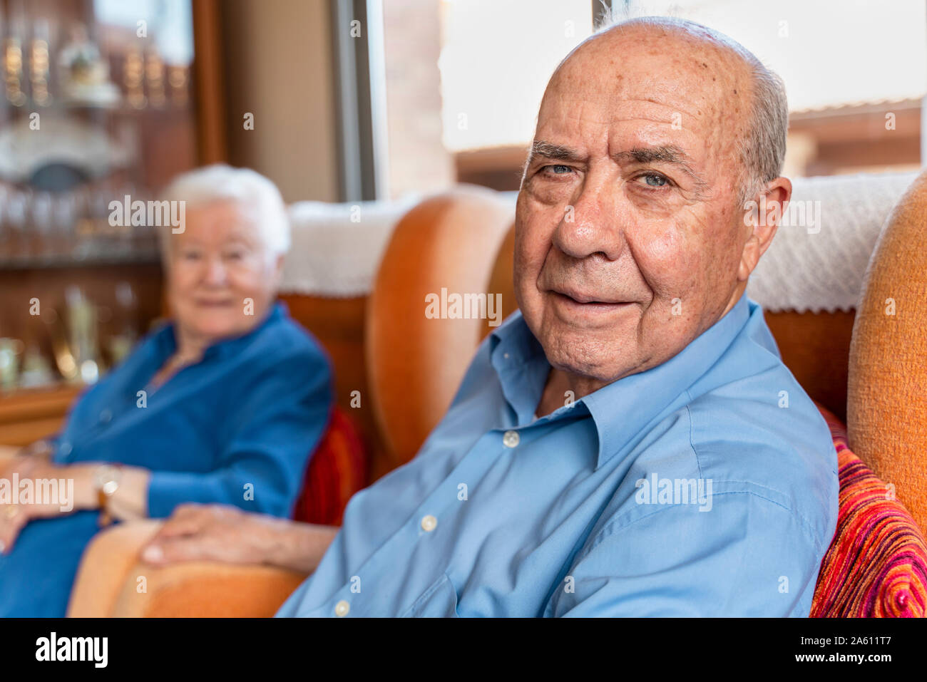 Vieil homme avec sa femme assise sur un fauteuil dans la salle de séjour Banque D'Images