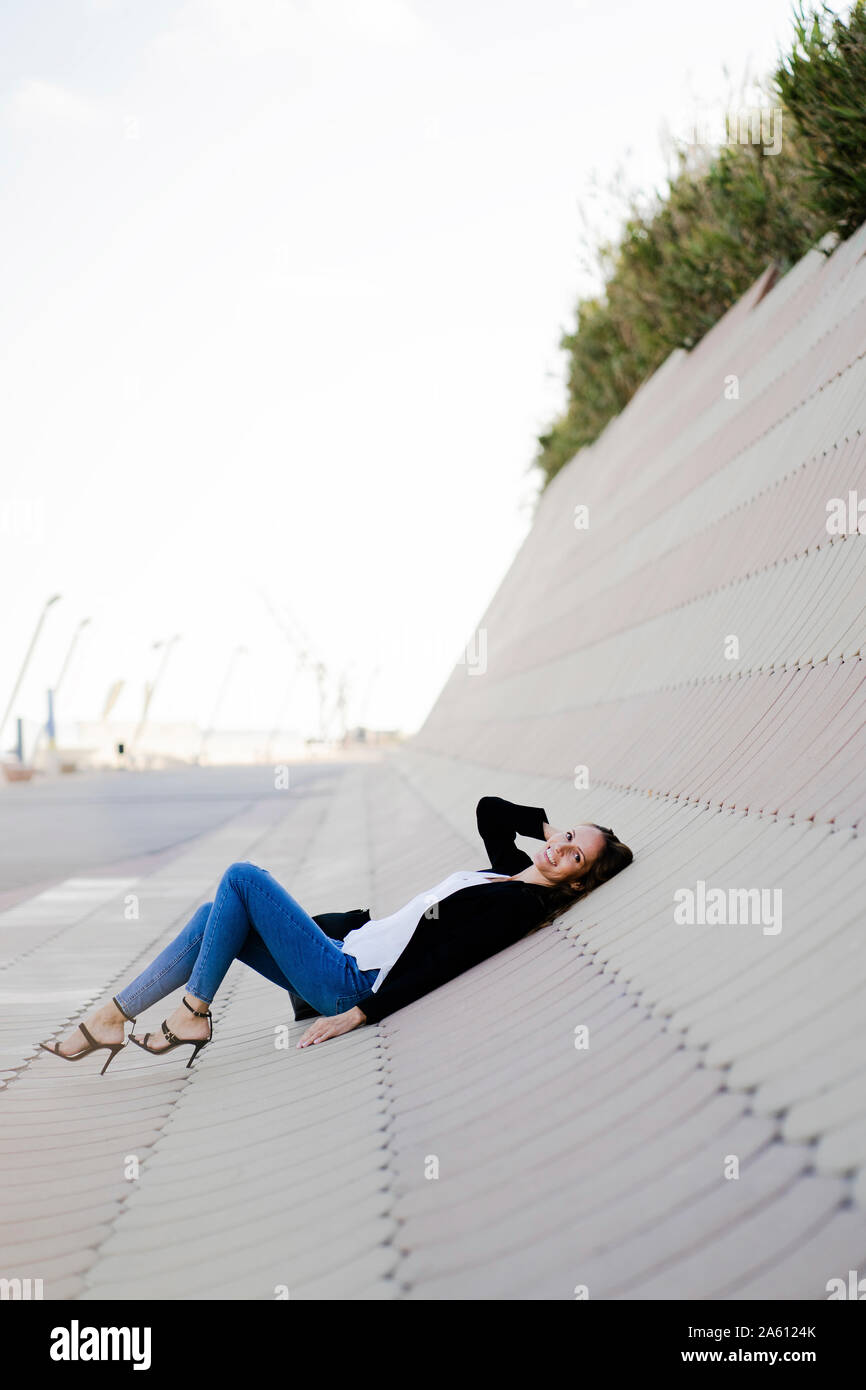 Businesswoman relaxing outdoors allongé sur béton Banque D'Images