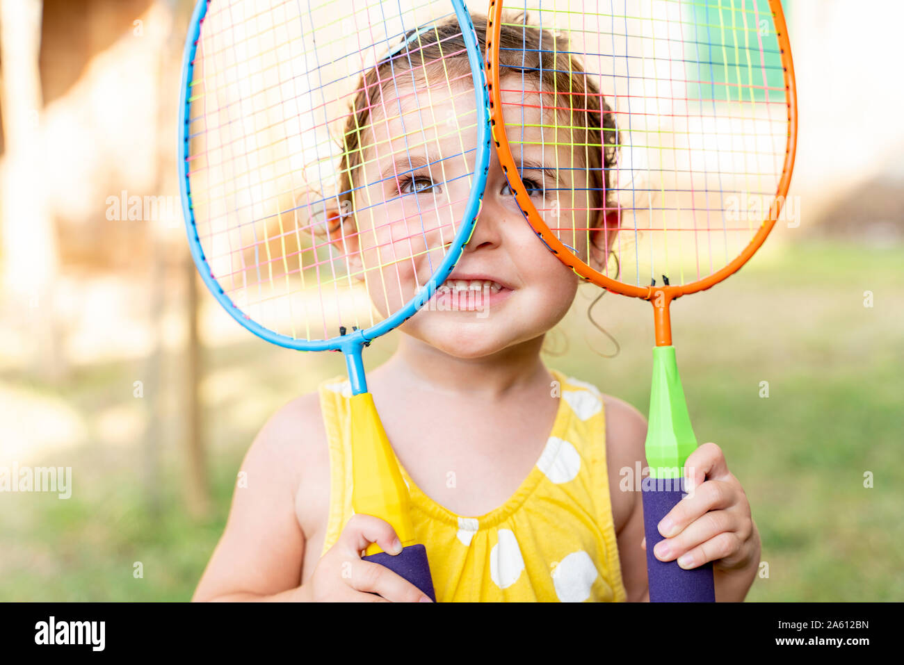 Petite fille jouant avec des raquettes de badminton en plein air en été Banque D'Images