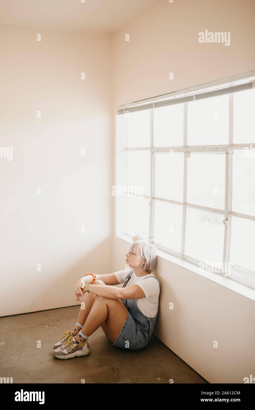 Jeune femme assise sur le sol dans une chambre Banque D'Images