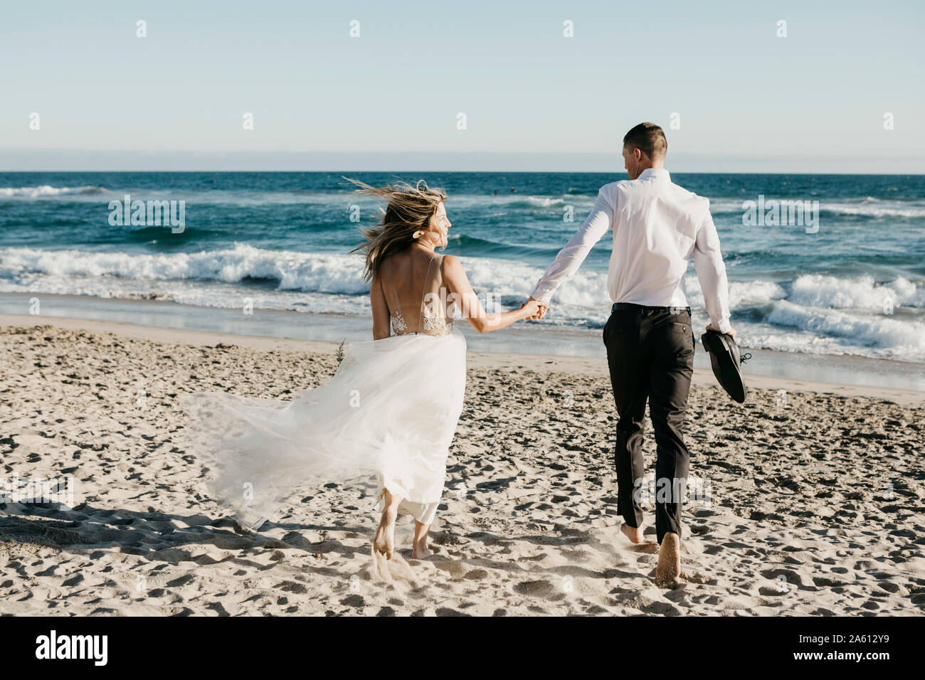 Vue arrière de l'époux et l'épouse d'exécution sur la plage Banque D'Images