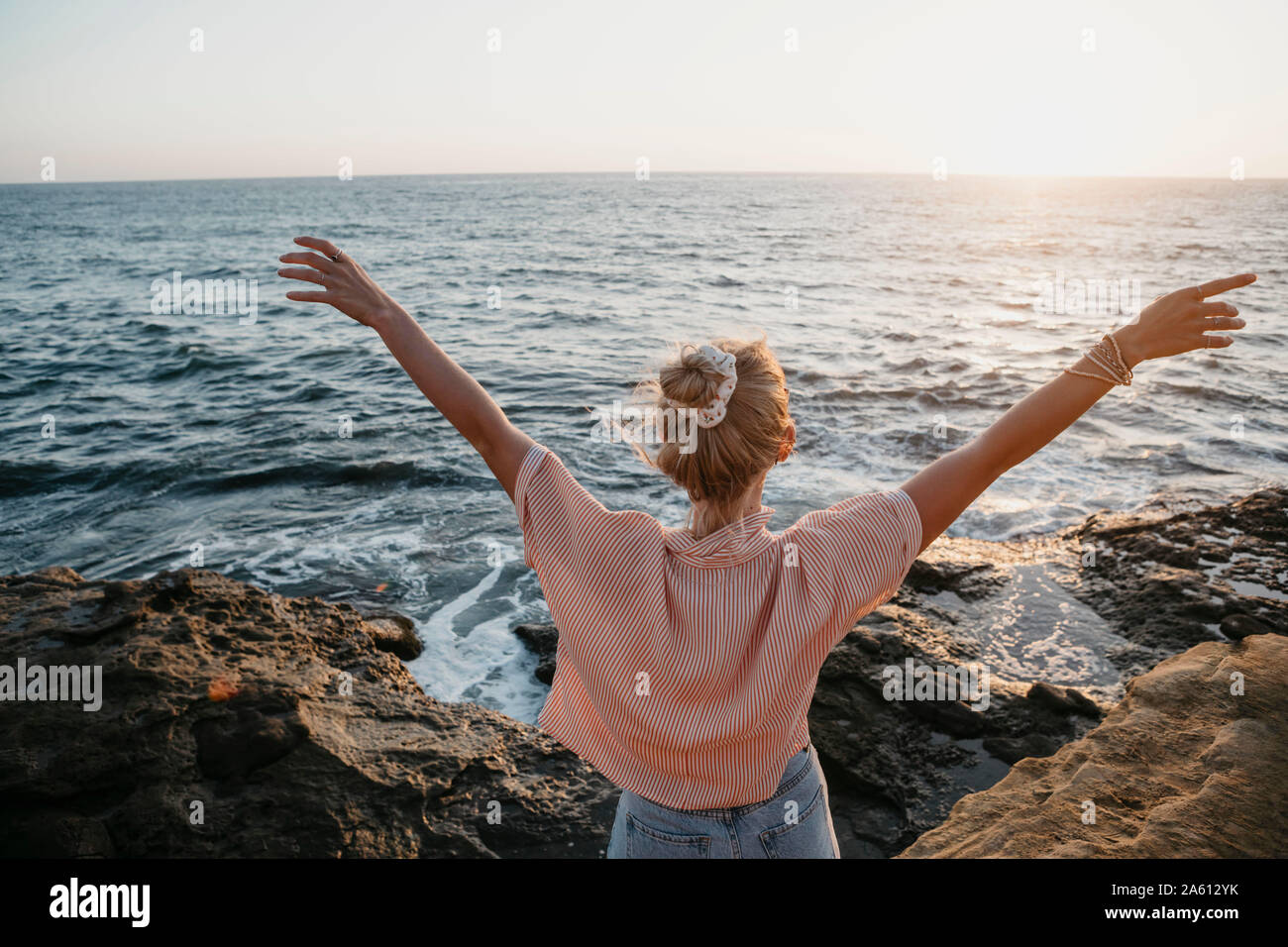 Vue arrière du jeune femme de la mer avec les bras levés, Sunset Cliffs, San Diego, California, USA Banque D'Images