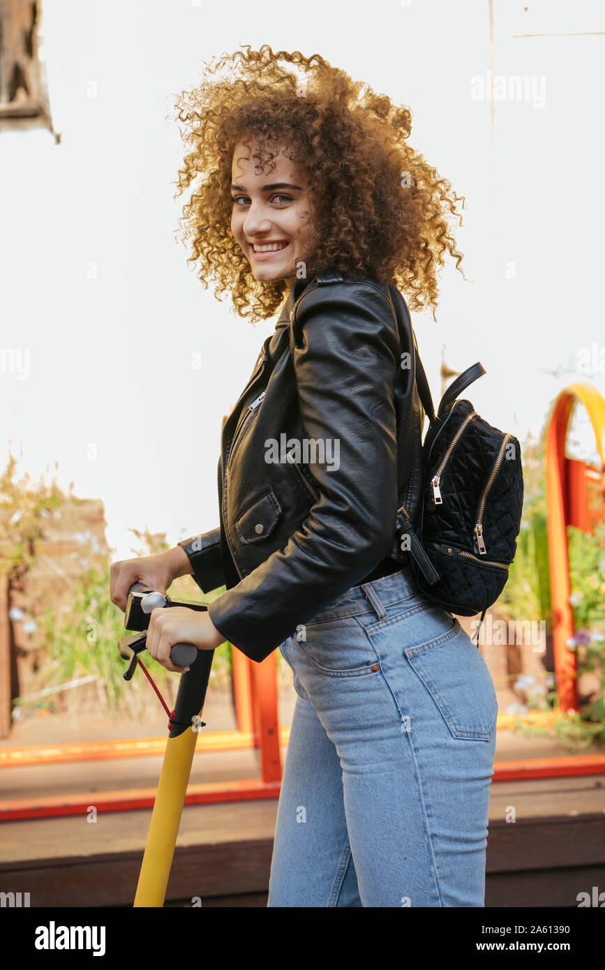 Portrait of smiling teenage girl avec sac à dos et scooter Banque D'Images