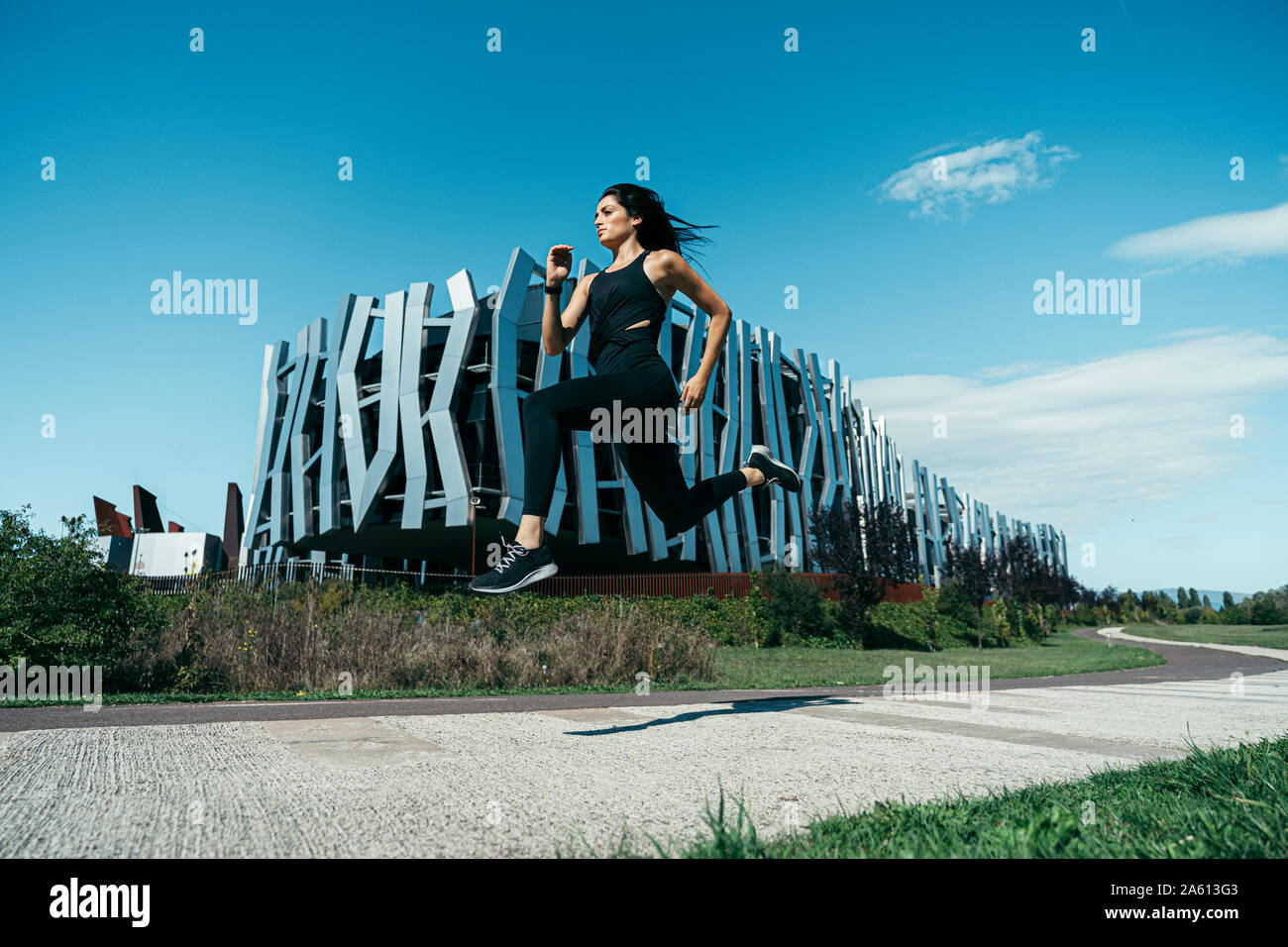 Young female jogger sur un comportement en face d'un immeuble moderne Banque D'Images
