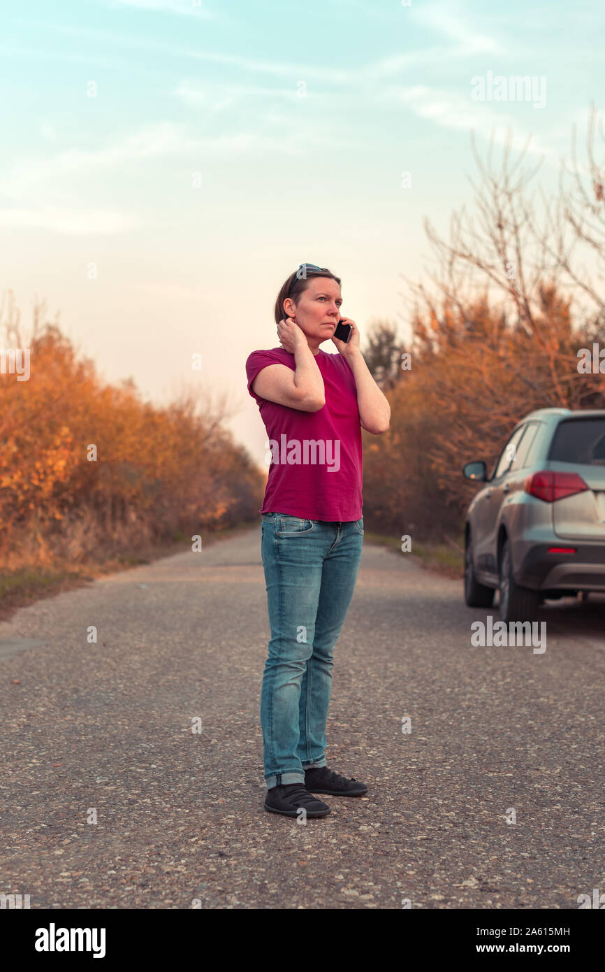 Femme perdue pendant la conduite automobile dans la campagne talking on mobile phone essayant d'obtenir de l'aide et l'assistance routière Banque D'Images