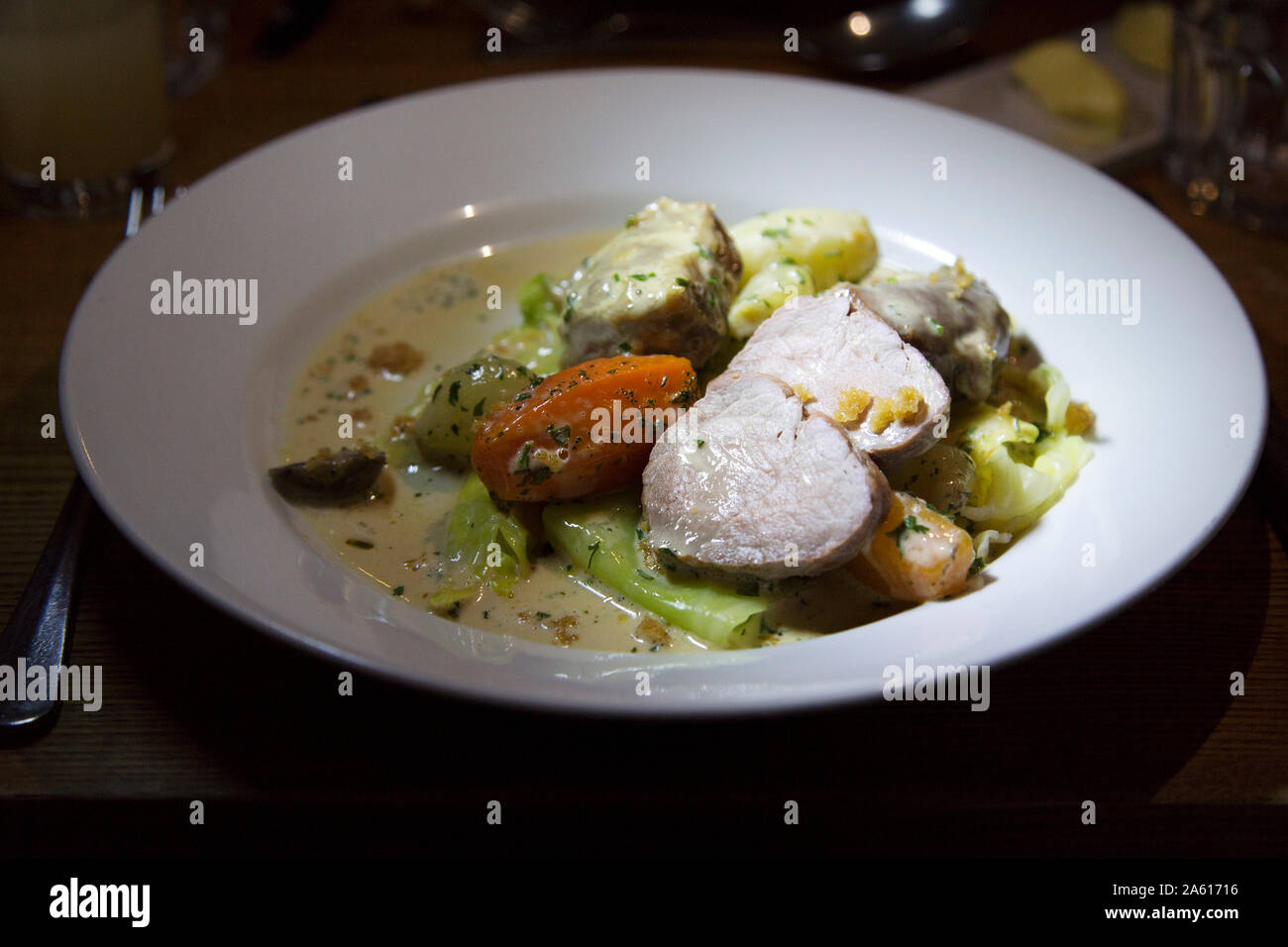 Une assiette de ragoût de porc avec des légumes d'hiver. Le plat comprend les carottes, les échalotes et une sauce crémeuse. Banque D'Images