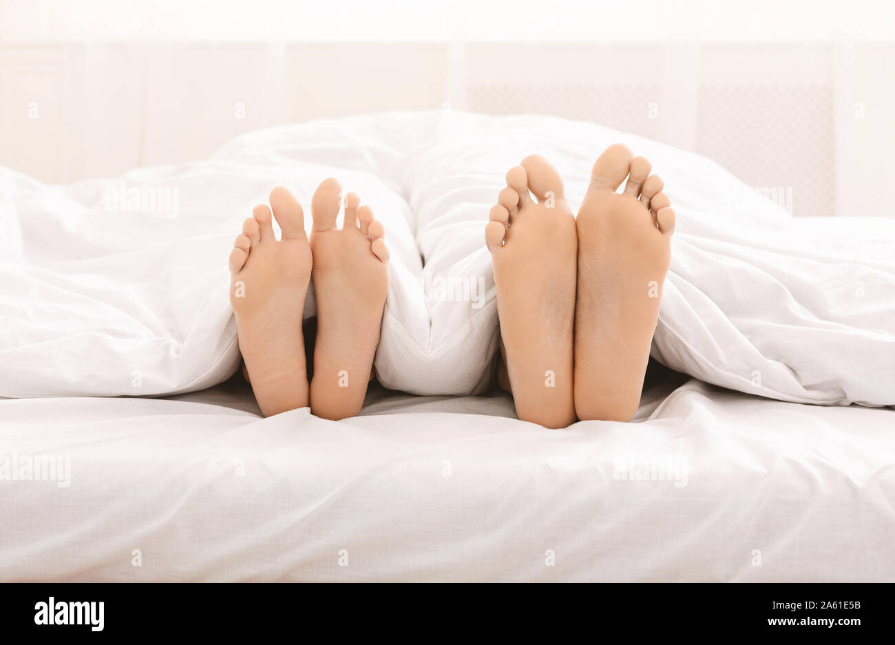 Les pieds mâles et femelles lying on bed sous couverture Photo Stock - Alamy