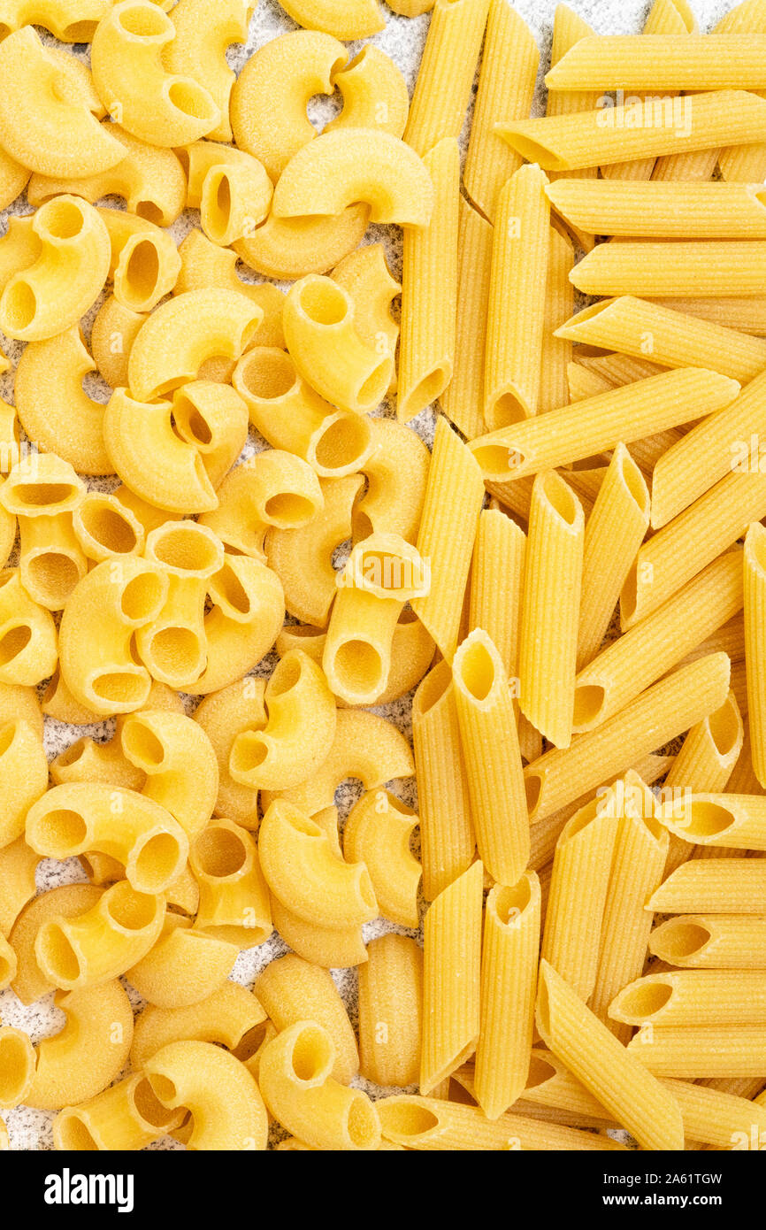 Types de pâtes alimentaires non cuites. Pâtes penne à sec et chifferi remplir le cadre. Mise à plat, vue du dessus, plein cadre. Banque D'Images