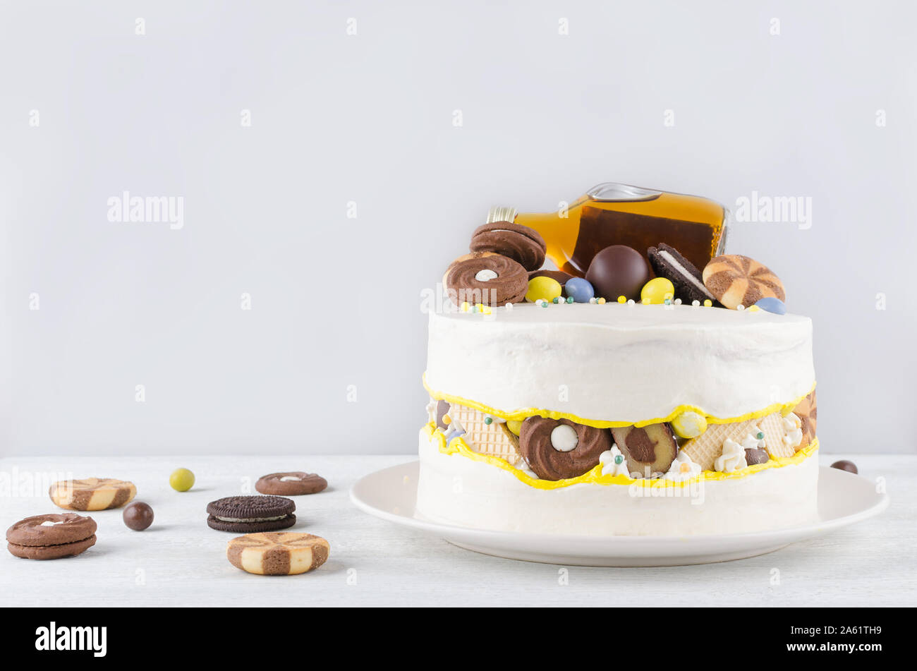 Drôle de gâteau avec une bouteille d'alcool, les sucreries et les cookies sur fond gris Banque D'Images