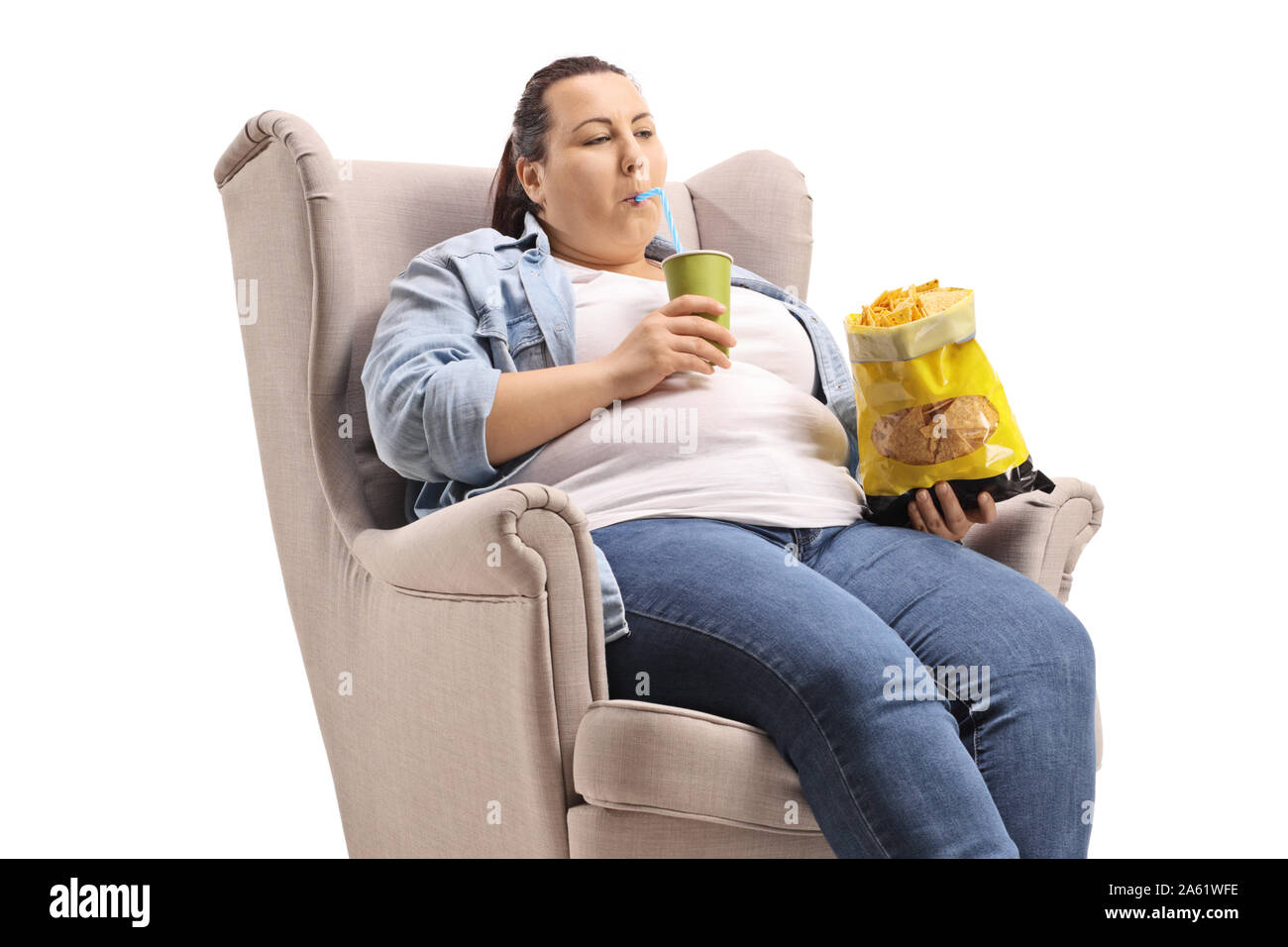 L'excès de femme assise dans un fauteuil de manger de la malbouffe isolé sur fond blanc Banque D'Images