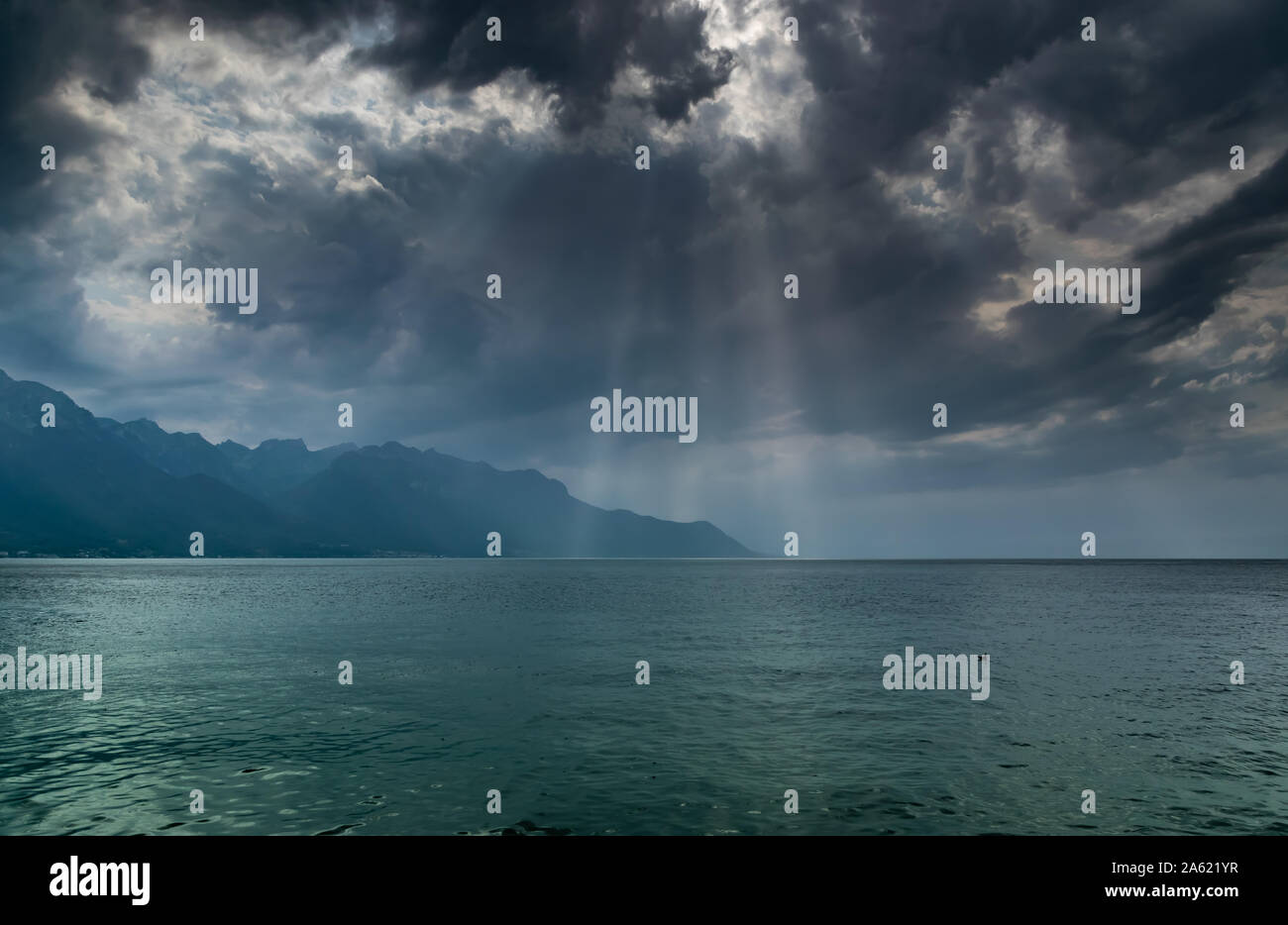 Paysage de montagnes des Alpes, le lac Léman,nuages sombres avec les rayons du soleil avant la pluie.cliché pris à partir de la rive du lac à Montreux, Suisse. Banque D'Images