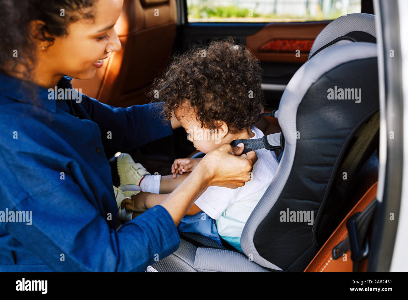 Vue latérale d'une mère du contrôle des courroies sur le siège de voiture de bébé avant un voyage Banque D'Images