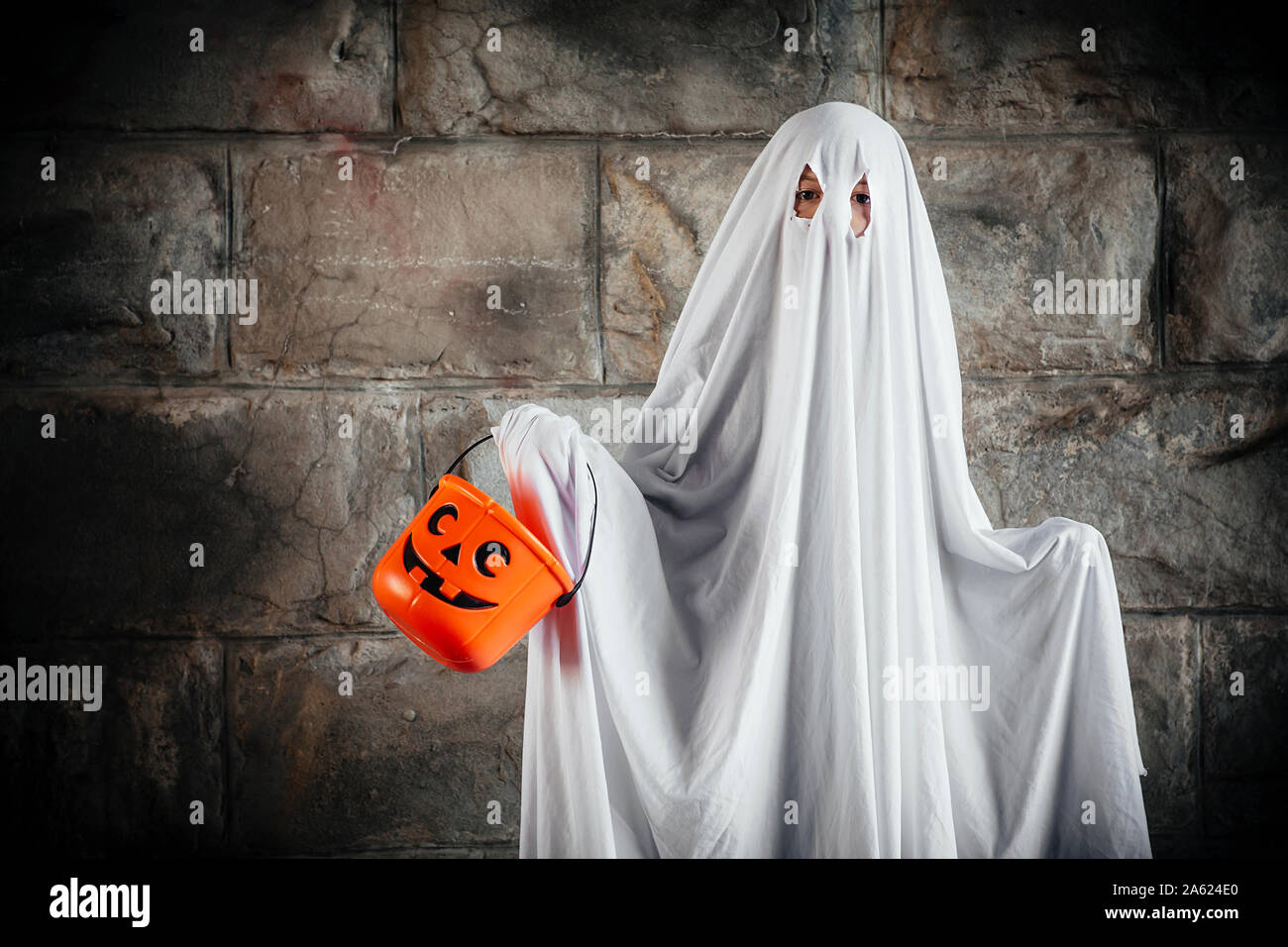 Jeune garçon vêtu d'un drap de lit pour être un fantôme, et tenant un seau  de potiron pour Halloween Photo Stock - Alamy