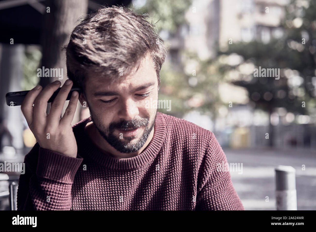 Séduisant jeune homme barbu en utilisant son smartphone dans le café Banque D'Images