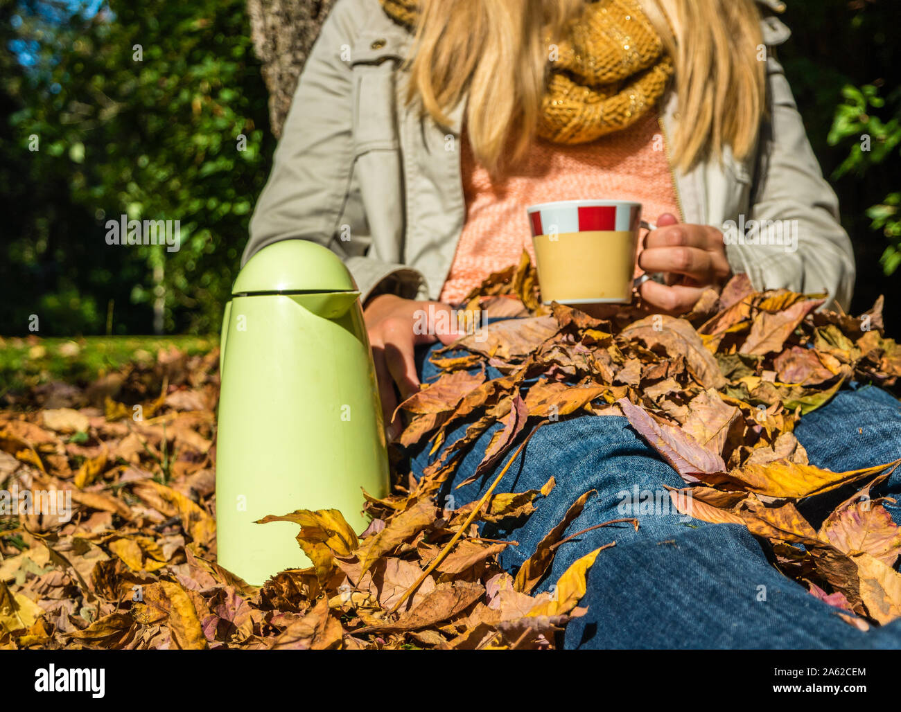 Femme avec thermos peut dans le parc en automne Banque D'Images