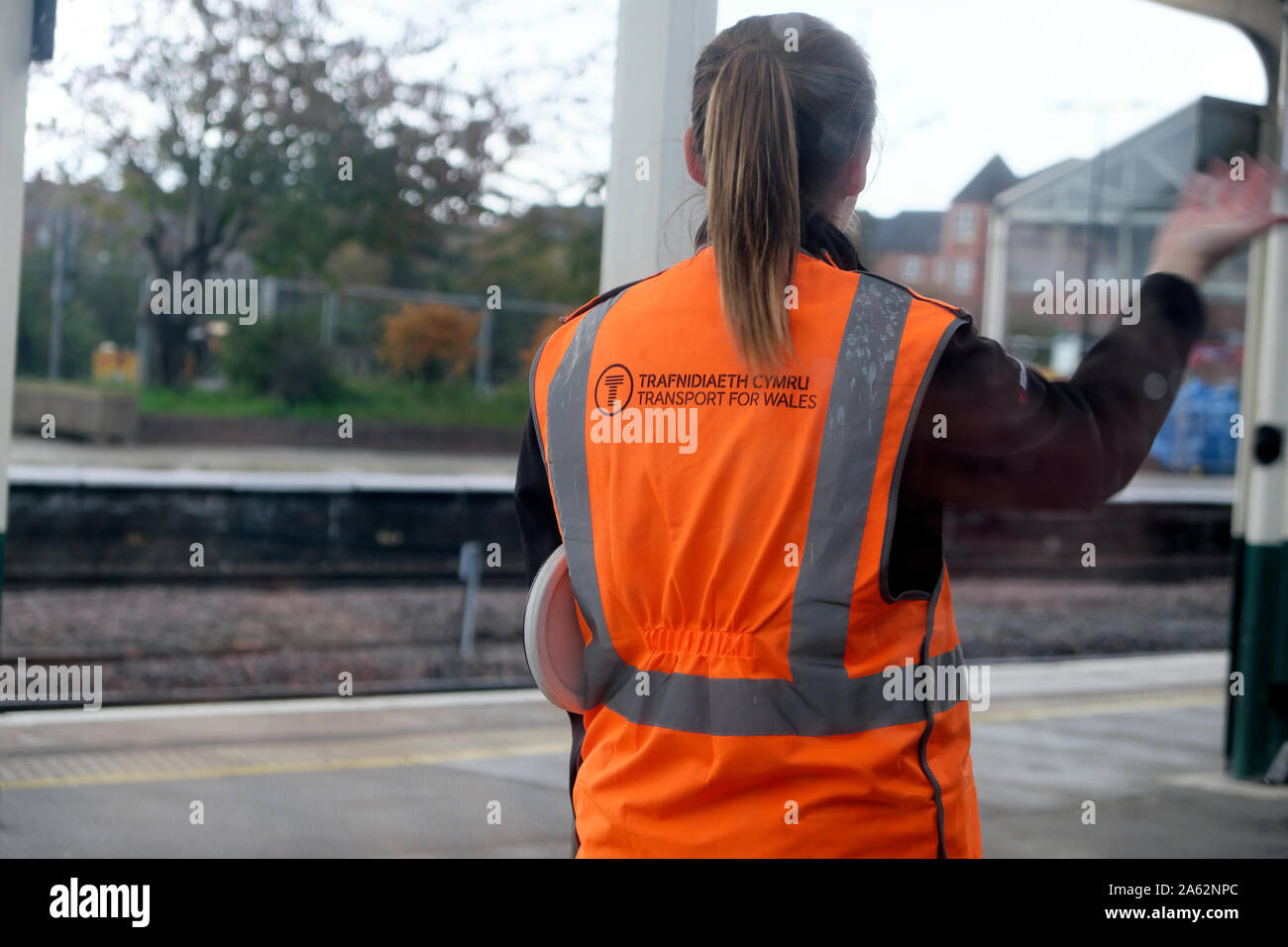 Vue arrière d'un TET Transport pour le pays de Galles jeune femme employée en agitant la main sur une plate-forme du train à la gare de Gwynedd au Pays de Galles UK KATHY DEWITT Banque D'Images