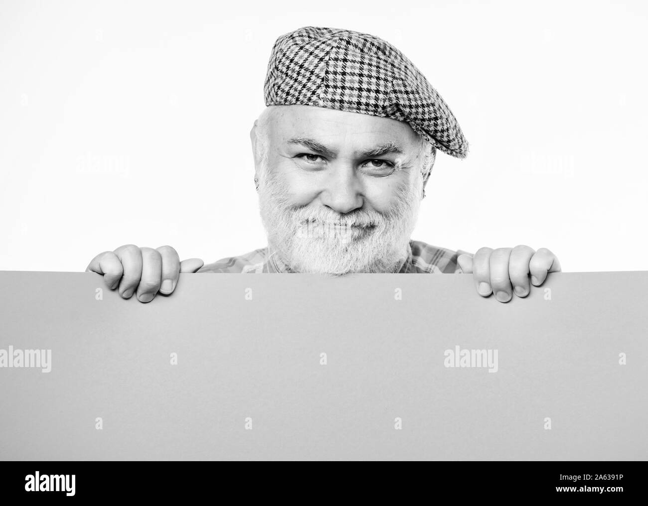 Cheerful présentateur de votre annonce. Copie espace apaiser l'information. recherche d'emploi. Besoin d'aide. Homme barbu Senior place annonce sur bannière. heureux homme mûr en rétro hat. Publicité. Banque D'Images