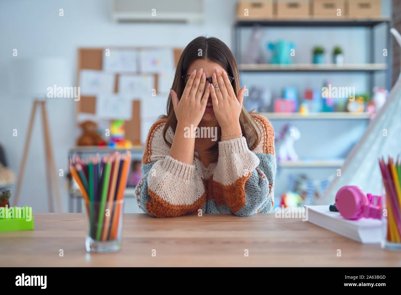 Belle Jeune femme portant l'enseignant chandail et verres assis sur 24 à l'école maternelle de frotter les yeux de la fatigue et des maux de tête, somnolence et fatigue expr Banque D'Images