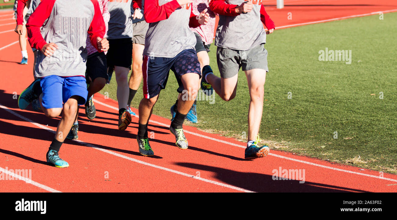Groupe de garçons courir vite sur une piste rouge tout en portant les crampons Banque D'Images