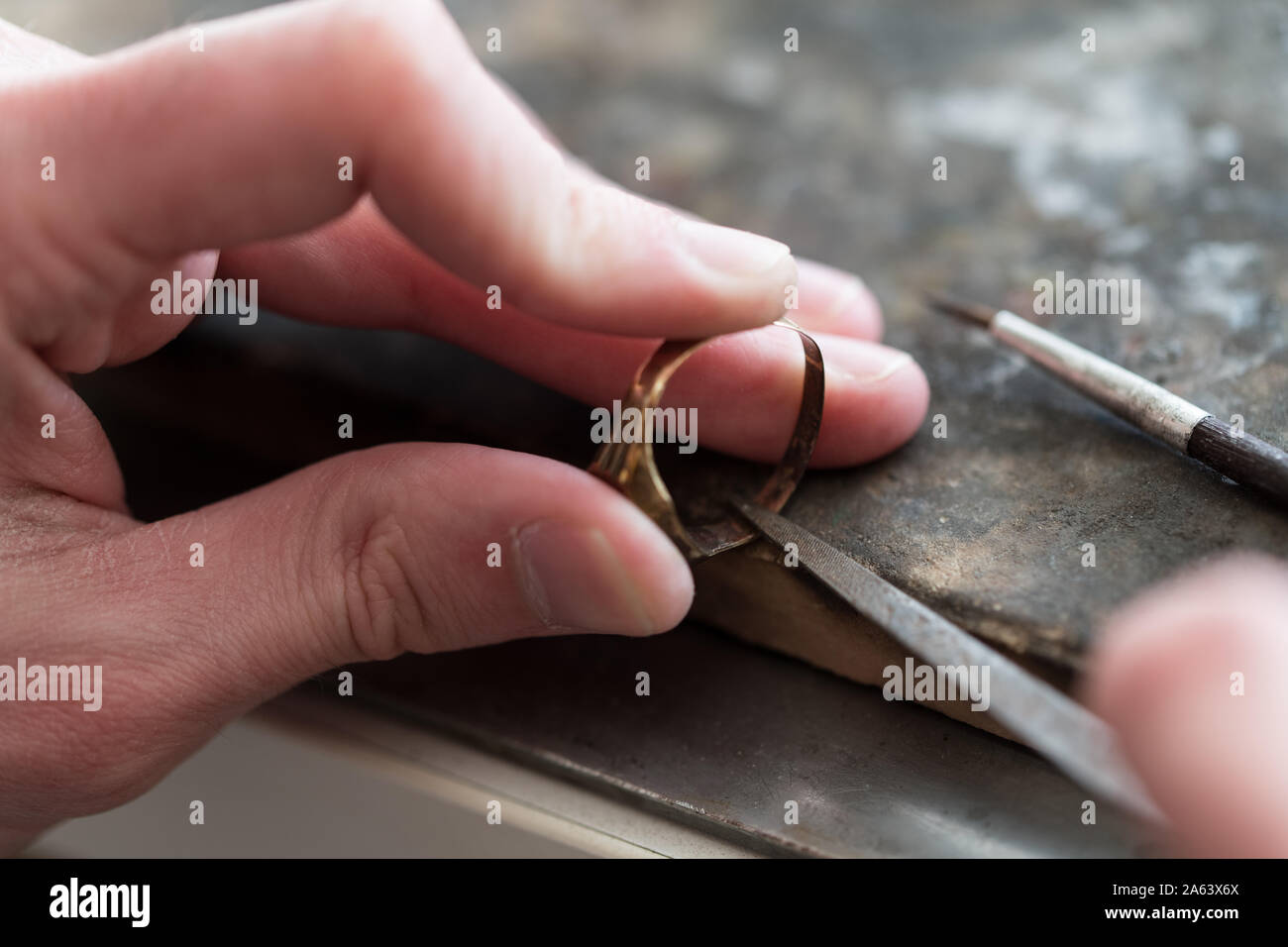 Goldsmith laborieux travaillant sur un anneau en or avec ses mains et des outils Banque D'Images