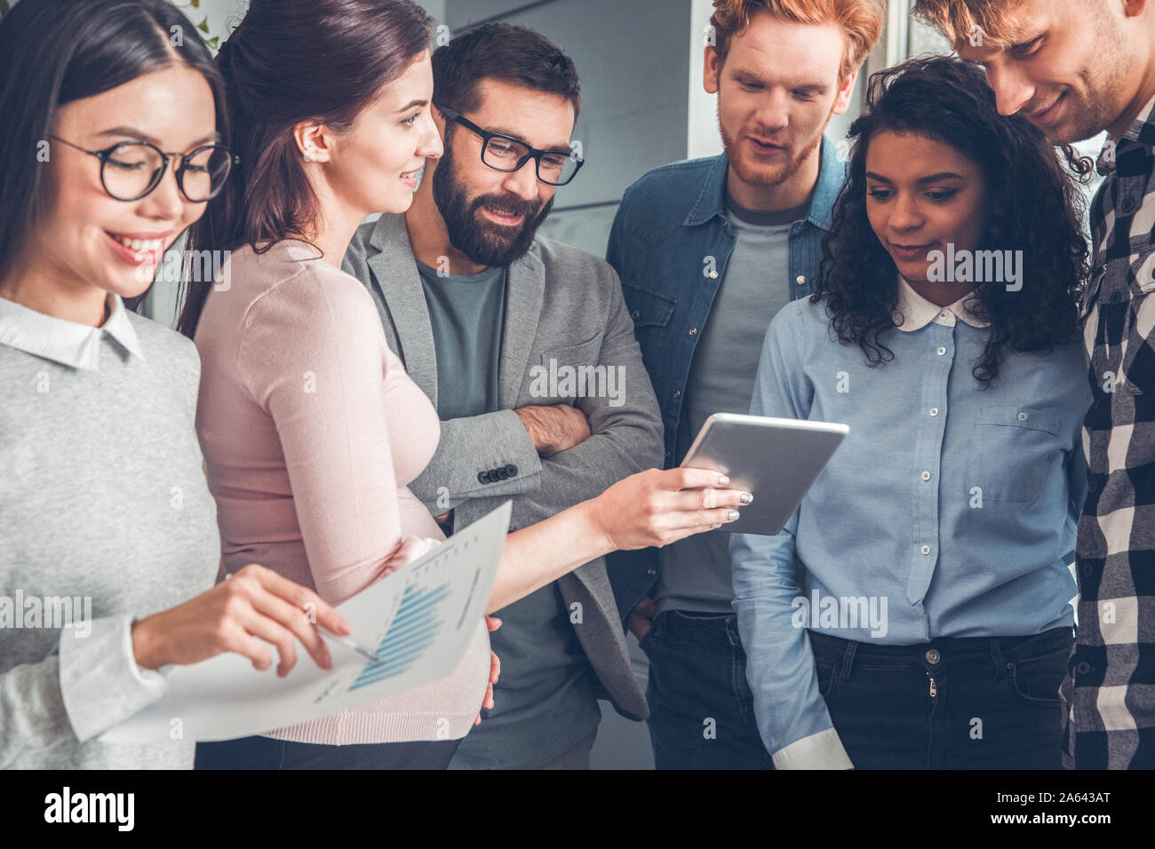 Startupers travailler ensemble au comité permanent du bureau femme enceinte montrant ses collègues des idées sur tablette numérique joyeuse Banque D'Images