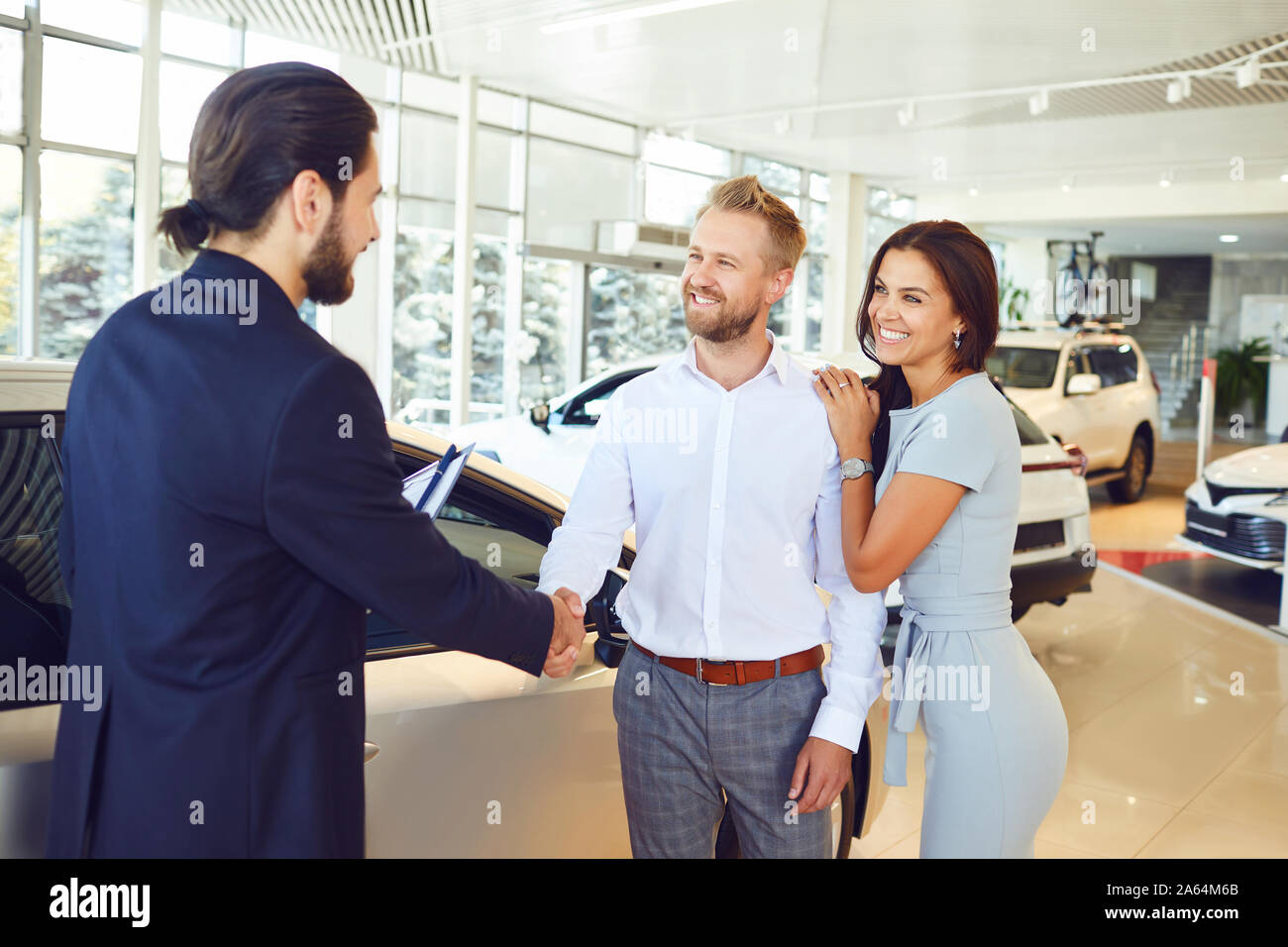 Un vendeur de voiture et un acheteur se serrer la main. Un couple achète une voiture Banque D'Images