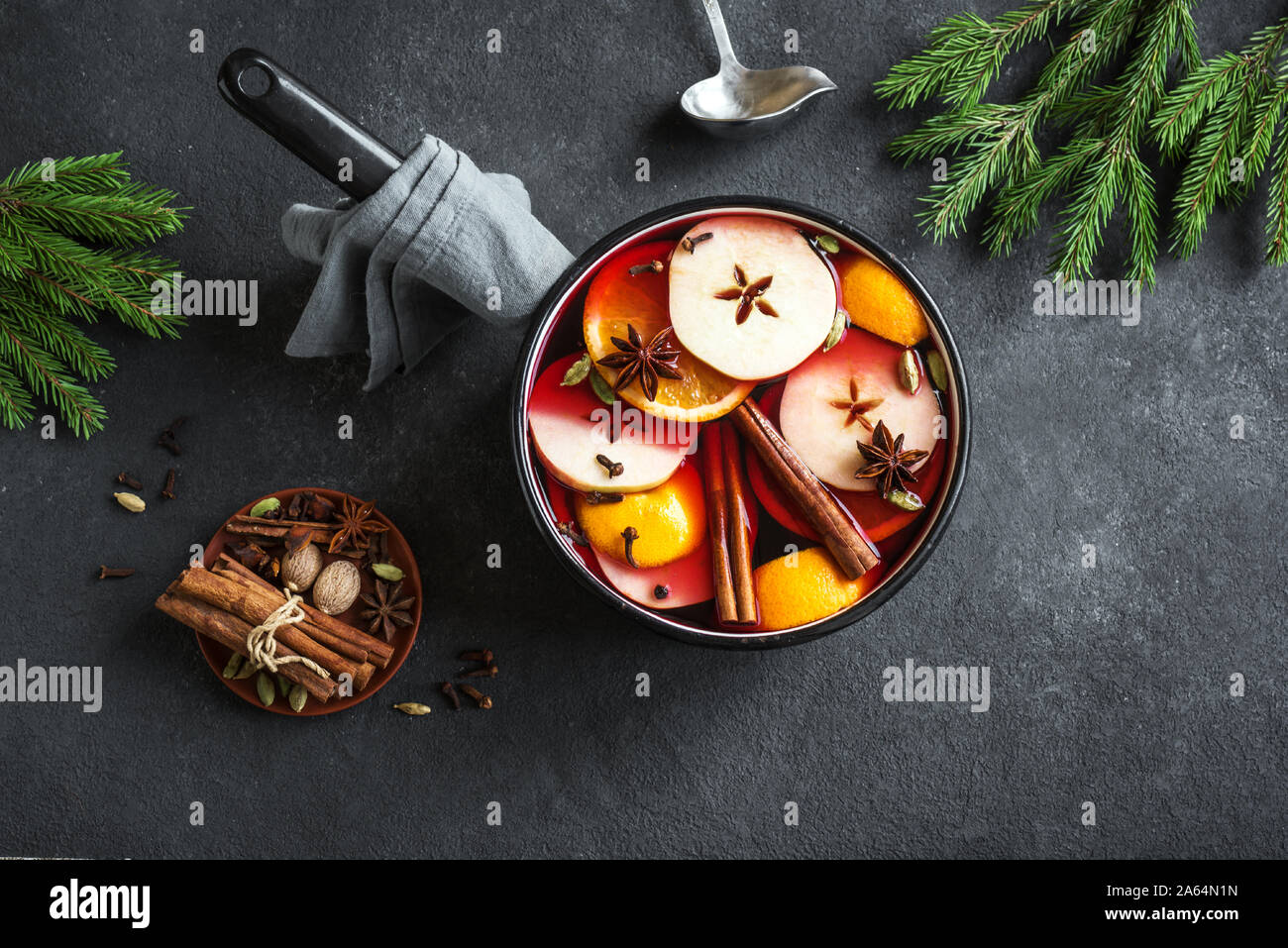 Vin chaud pour Noël et vacances d'hiver. Boire de vin chaud avec des fruits et d'épices en cocotte sur fond noir, vue du dessus, copiez l'espace. Banque D'Images