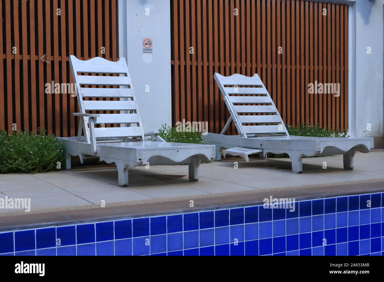 Libre de deux chaises longues en bois vide placé sur la piscine sur sunny day Banque D'Images