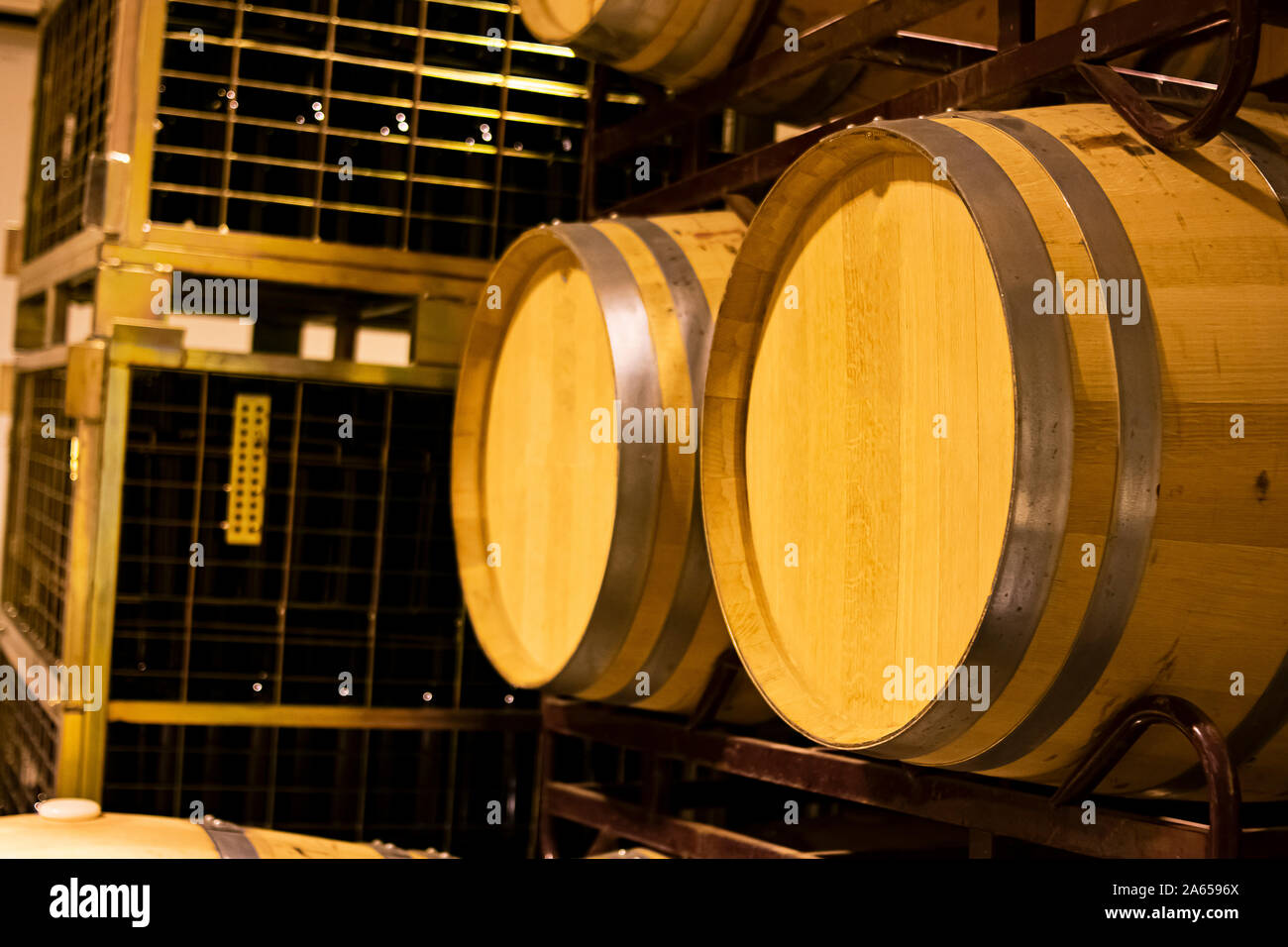 Barriques de chêne américain pour le vieillissement et le vieillissement du vin dans une cave empilés sur des étagères métalliques Banque D'Images