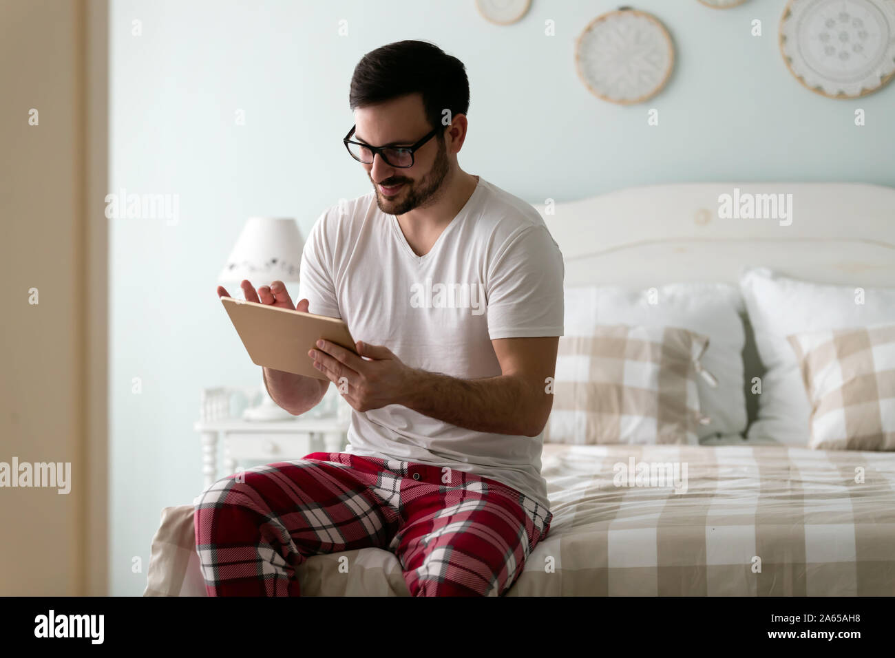 Handsome Young man using digital tablet on bed Banque D'Images