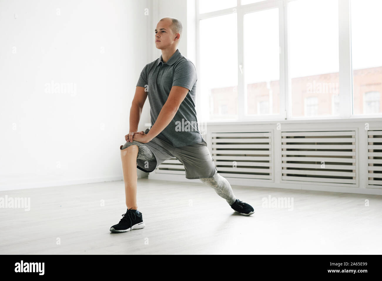 Jeune homme handicapé avec des prothèses et de l'exercice permanent dans la chambre Banque D'Images