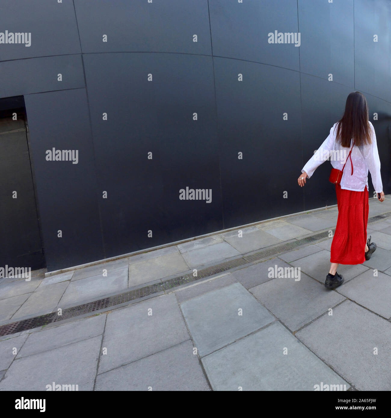 Londres, Angleterre, Royaume-Uni. Jeune femme en blanc top et jupe rouge dans le Strand Banque D'Images