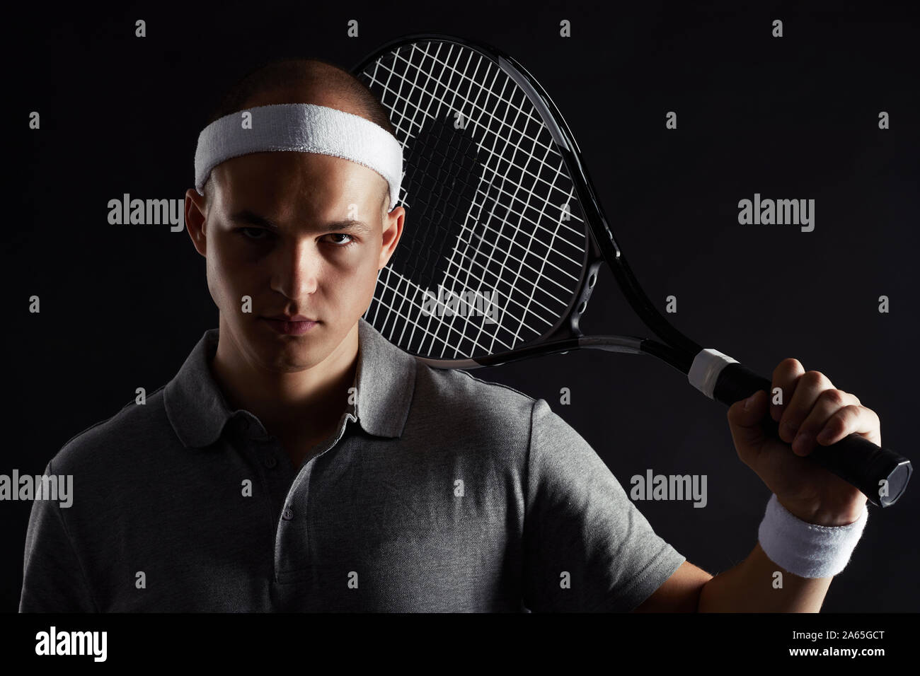Studio shot of young sportsman avec racket à l'encontre de l'appareil photo à l'arrière-plan noir Banque D'Images